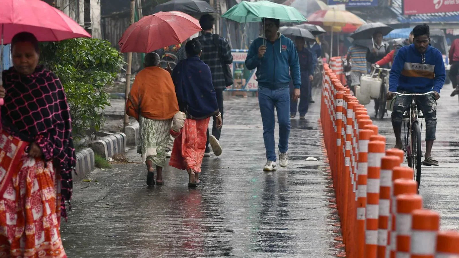 उत्तर प्रदेश में बारिश और तेज आंधी के दौरान सड़क पर चलते लोग