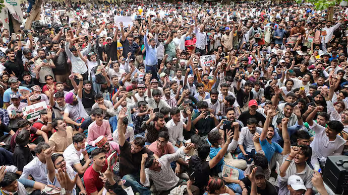 नई दिल्ली के जंतर-मंतर पर कॉकरोच जनता पार्टी के समर्थक बैनर और झंडों के साथ शांतिपूर्ण धरना देते हुए, आसपास भारी पुलिस और CRPF सुरक्षा, बैरिकेडिंग और सुरक्षा व्यवस्था का दृश्य।